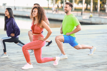 Fototapeta premium Group of young sporty people training together outdoors