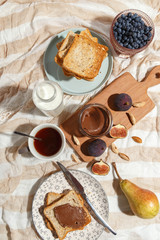 Appetizing toasts with chocolate paste, tea, figs, blueberries and almonds on the table.