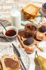 Appetizing toasts with chocolate paste, tea, figs, blueberries and almonds on the table.