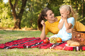 Happy mother and her little daughter at picnic in park