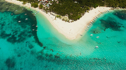 Beach with tourists and boats on a tropical island, clear blue water. Daco island, Philippines....