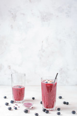 Glasses of acai smoothie on light background