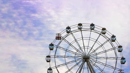 Empty Observation wheel on the background of blue sky with white clouds. Horizontal with copy space for text of design about theme park, amusement. Summer. Day time.