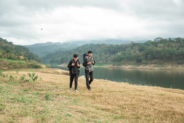 Fototapeta na wymiar Two asian travelers standing near lake at sunny day