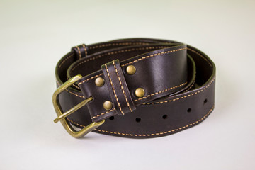 dark brown stitched leather belt with yellow buckle and rivets on a white background