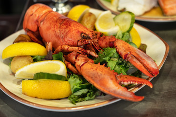 Lobster with lemon and green salad on the plate.