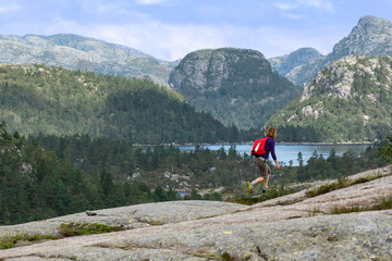 Fototapeta premium Girl on the shore of mountain lake, Norway. Way to Preikestolen rock.