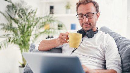 Man listening to music and using laptop in the living room.