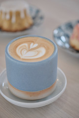 Hot cappuccino coffee cup with tree shape latte art milk foam on wood table near window in garden at cafe restaurant