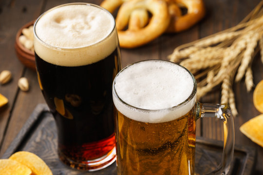 Two glasses of beer - light and dark with various snacks.