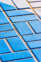 Texture of blue brick tiles and yellow sand with copy space, to be used as background. Selective focus