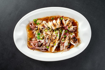 Chinese Chaoshan home cooking, a plate of oyster sauce steamed small squid on a black background
