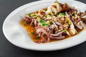 Chinese Chaoshan home cooking, a plate of oyster sauce steamed small squid on a black background