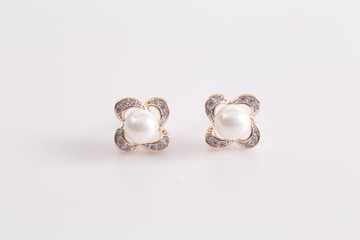 Heart shaped gold earrings with diamonds and pearl at the ear