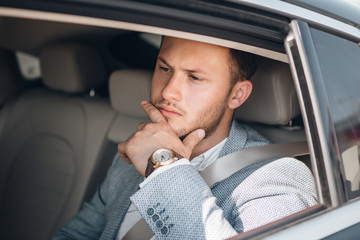 Portrait of a happy young businessman in a suit on a rear seat