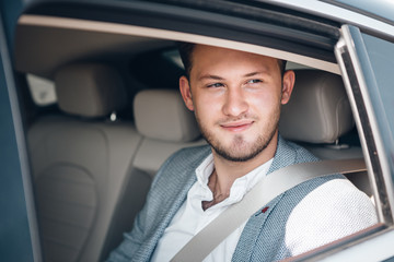 Portrait of a happy young businessman in a suit on a rear seat
