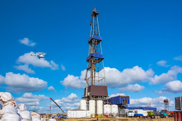 In the foreground is a drilling rig for drilling oil and gas wells with various equipment and...