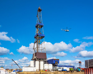 In the foreground is a drilling rig for drilling oil and gas wells with various equipment and...