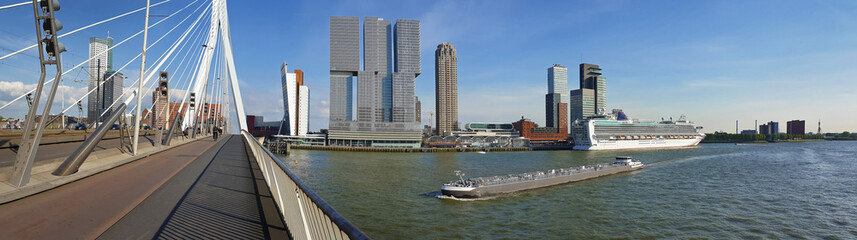 Stadsgezicht panorama vanaf de Erasmusbrug over de Maas in Rotterdam, Nederland. Hoge moderne gebouwen aan de horizon en grote schepen die de Erasmusbrug oversteken.