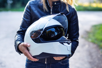 Woman in leather jacket holds motorcycle helmet