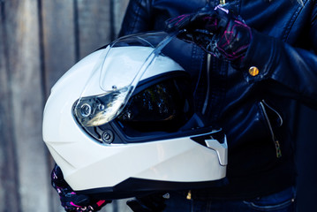 Fototapeta na wymiar Woman in leather jacket holds motorcycle helmet