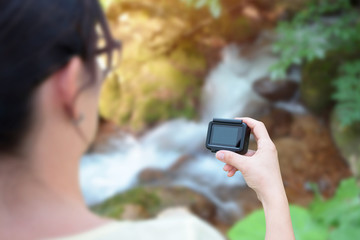 Woman filming nature with action camera concept. Blank screen for mockup.