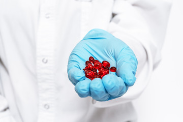 Pharmacist holds a handful of red pills for a patient. Placebo drugs concept. Treatment and health care. medicine for various diseases hospital concept.