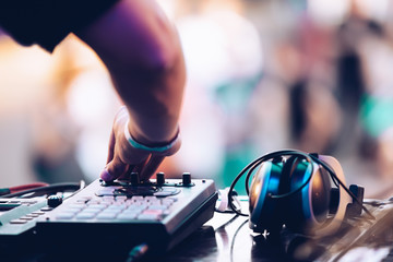 Electronic music festival in summer.EDM dj plays set on stage at concert.Disc jockey playing popular music on midi controller device & headphones on table.Professional audio equipment for djs