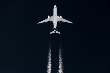 Fototapeta na wymiar Airliner mit Kondensstreifen vor dunklem himmel 