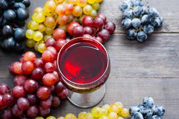glass of red wine and grapes on black wooden table background