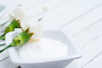 cosmetic cream and white carnation flowers on bright wooden table