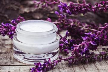 Obraz na płótnie Canvas Cosmetic cream and fresh lavender wildflowers on a wooden background. Face cream.