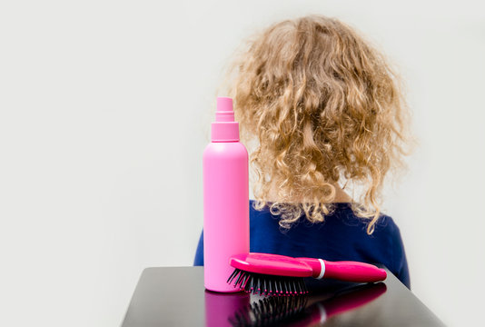 Curly Hair Girl Child With Curly Hair Spray Balm And Brush To Help Combing Messy Fuzzy Hair Concept. Indoors Minimal White Background.