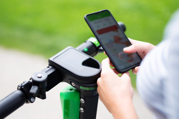 Junge Frau entsperrt einen Elektroroller mit einem Smartphone 