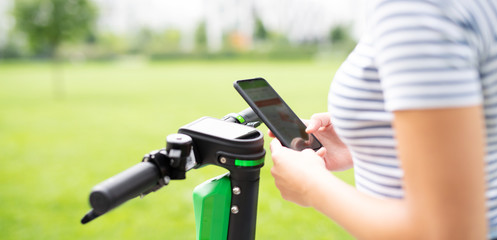 Junge Frau entsperrt einen Elektroroller mit einem Smartphone 