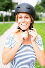 Junge Frau zieht einen Helm an um mit einem E-Scooter zu fahren 