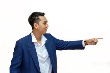 relaxed young asian businessman points and looks to side while standing on white background, portrait picture