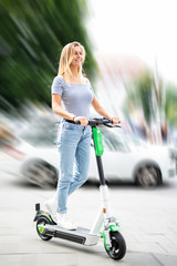 Junge Frau fährt mit einem E-Roller durch die City 