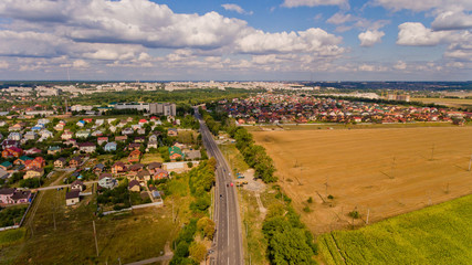 Aerial view of cityscape with road and field and clouds.