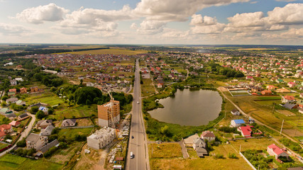 Aerial view of cityscape with road and field and clouds.