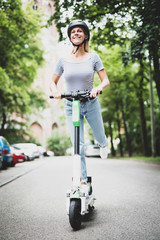 Junge Frau mit Helm fährt auf einem elektrischen Roller 