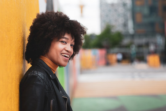 Portrait Of African American Young Adult Leaning On Bright Yellow Wall