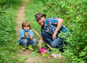 Little boy and father in nature background. Gardening tools. Spring gardening routine. Planting flowers. Gardening hobby. Dad teaching little son care plants. Little helper in garden. Farm family