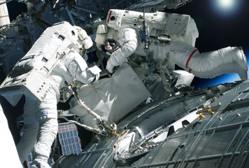 Two astronauts in spacesuits, in outer space. Elements of this image were furnished by NASA