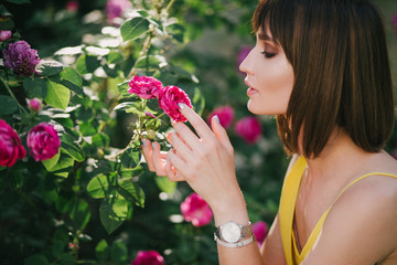 Woman beauty with tattoo on hand near roses in garden.