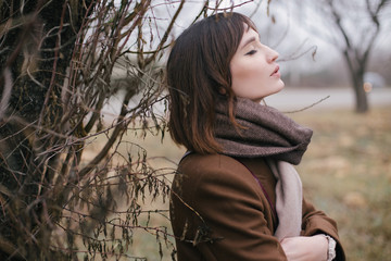 Woman in brown stylish cashmere posing on autumn background.