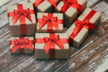 Some gift boxes wrapped in brown craft paper and tie red satin ribbon. Decorative wooden background. Your text space. Set of presents.