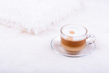 Top view of cup of latte coffee on white furry carpet