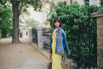 Beautiful woman in yellow jumpsuit posing on city streets.