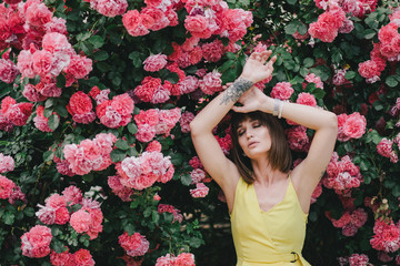 Woman beauty with tattoo on hand near roses in garden.